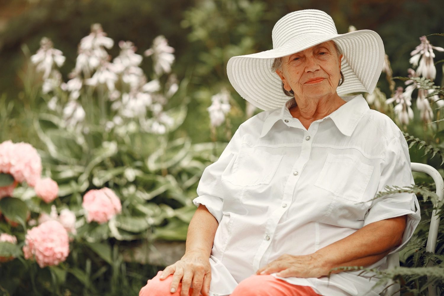 A resident sitting in the garden in a wide sun hat