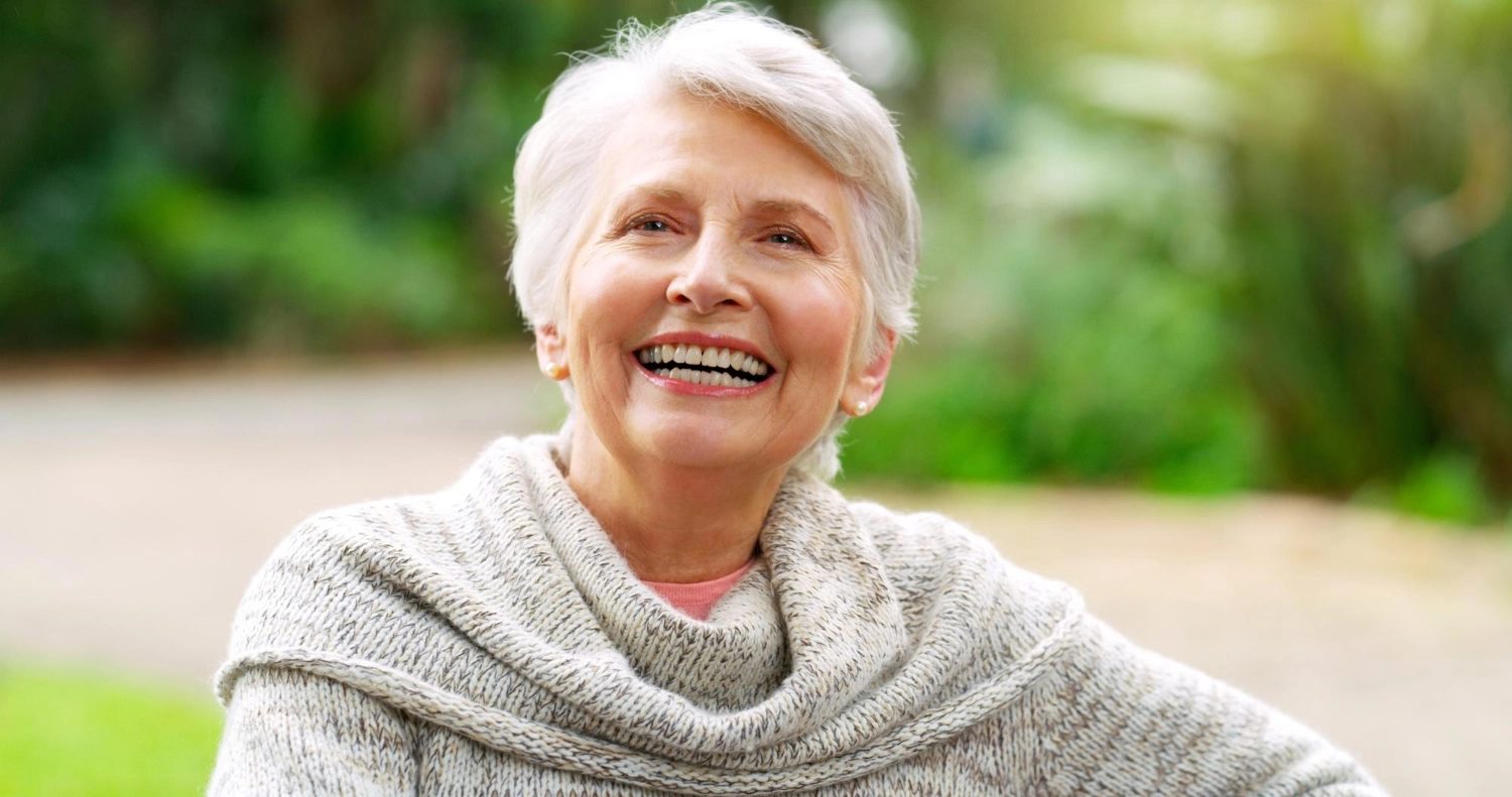 A resident laughing in a soft cream sweater