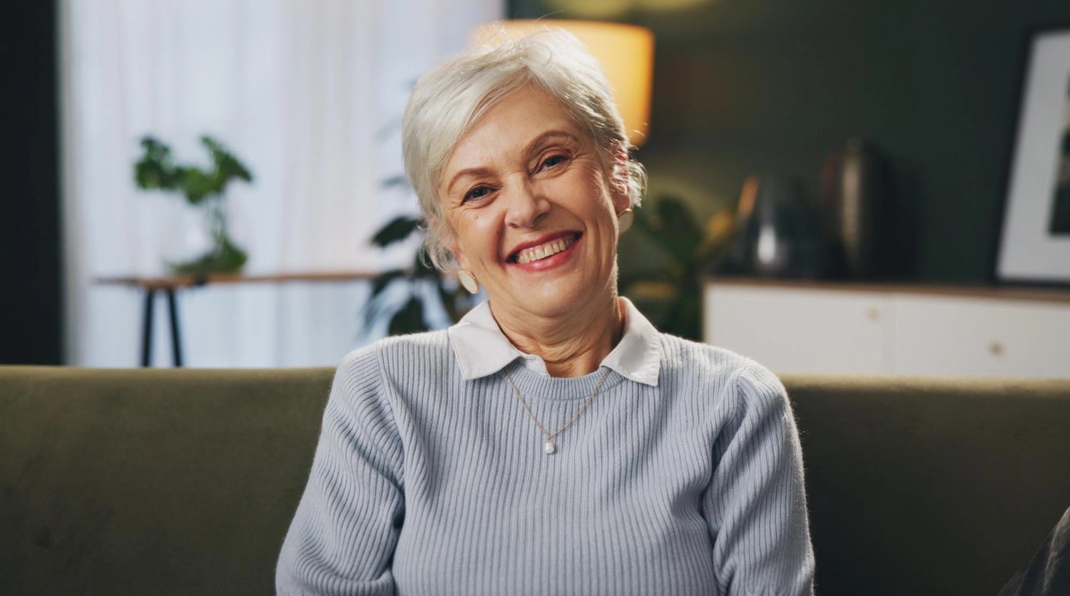 A resident smiling in a softly lit sitting room